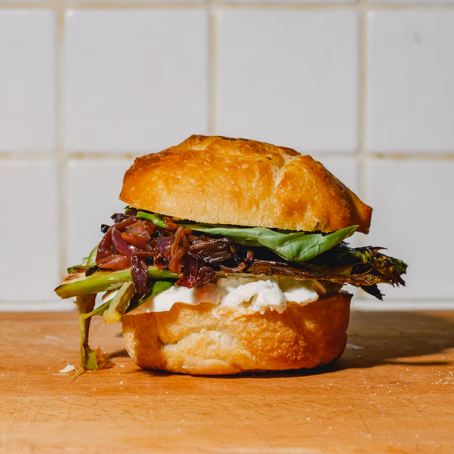 Belegtes Brötchen mit gegrilltem Gemüse, roten Zwiebeln und frischem Grün