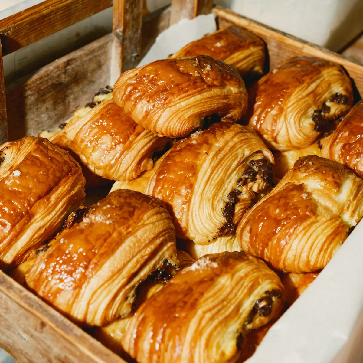 Goldbraun gebackene Croissants und Pain au Chocolat in einer Holzkiste
